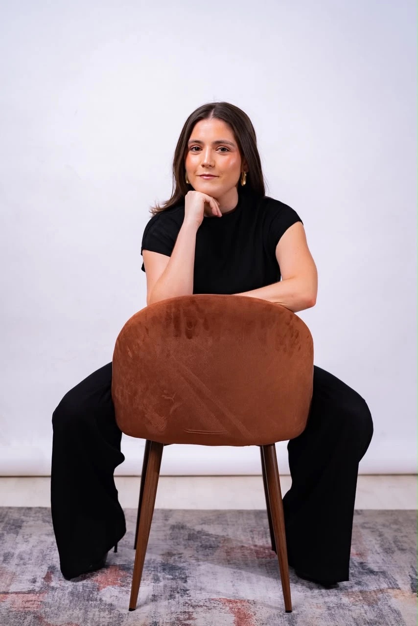 Daniela de la Peña sentada al revés en una silla, con la barbilla apoyada en la mano
