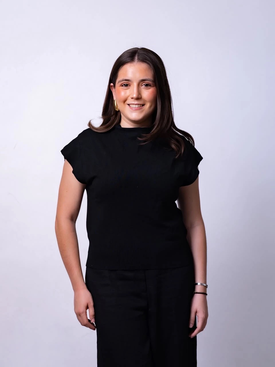Daniela de la Peña, psicóloga clínica, sonriendo de pie frente a un fondo claro